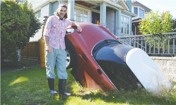  ?? — JoHn MACkIe/PnG ?? East Vancouver resident Andrew Huggard installed a Mini Cooper as a sculpture in his front yard. There are two parts to the car, which is a fibreglass replica, not the real deal. He also has a nine-foot beer bottle, which can be glimpsed over his shoulder.