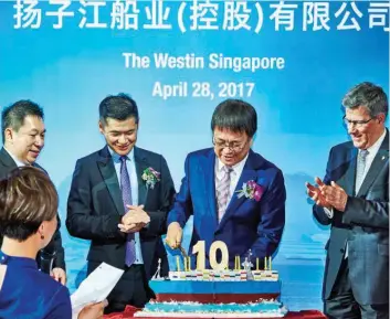 ?? YANGZIJIAN­G ?? Ren (cutting the cake, with Letian on his right) celebrate the company’s 10th anniversar­y of listing in 2017