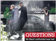  ??  ?? QUESTIONS ‘Mr Black’ confronted near hall