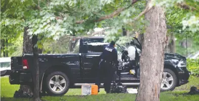  ?? ADRIAN WYLD / THE CANADIAN PRESS ?? An RCMP police officer looks in the cab of a pickup truck on the grounds of Rideau Hall on July 2. A man who had
trafficked in QAnon material was charged with ramming the truck into the grounds of the prime minister.
