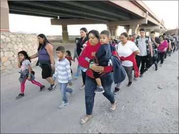  ?? Carolyn Cole Los Angeles Times ?? ABOUT 50 men, women and children seeking asylum are led by Border Patrol agents to a holding area after entering the United States. The president has largely failed to deter migration to the southern border.