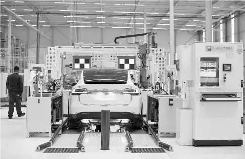  ??  ?? A Tesla Model X sports utility vehicle (SUV) undergoes wheel alignment checks during assembly for the European market at the Tesla Motors factory in Tilburg, Netherland­s on Dec. 9, 2016. — WP-Bloomberg photo