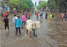  ?? Reuters ?? People wade through a water-logged road after heavy rainfall in Mumbai yesterday.