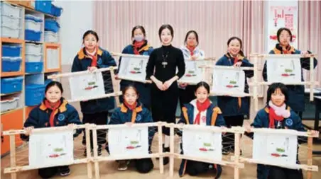  ?? ?? Fan Dongmei (center) poses for a photo with her students, showcasing their needlework after class. — Photos by Chen Haojun and Lu Jinhui