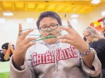  ??  ?? Terrell Shirley participat­es in a string game during the Restoring and Celebratin­g Family Wellness program at the Office of Diné Youth in Shiprock.