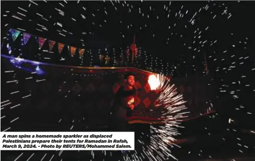  ?? ?? A man spins a homemade sparkler as displaced Palestinia­ns prepare their tents for Ramadan in Rafah, March 9, 2024. - Photo by REUTERS/Mohammed Salem.