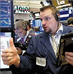  ?? AP/RICHARD DREW ?? Trader Michael Milano works Friday on the floor of the New York Stock Exchange, where the Dow gained 747 points after losing 660 on Thursday.