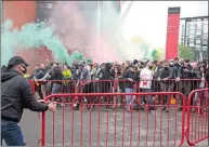  ?? BARRINGTON COOMBS/AP PHOTO ?? Fans move barriers outside the ground as they let off flares whilst protesting against the Glazer family before their Premier League match against Liverpool on Sunday.