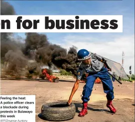  ?? Afp/zinyange Auntony ?? Feeling the heat: A police officer clears a blockade during protests in Bulawayo this week