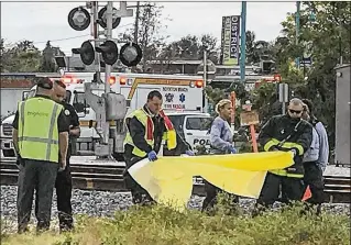  ?? GEORGE BENNETT / THE PALM BEACH POST ?? Boynton Beach Fire Rescue personnel prepare to cover the body of a bicyclist who was struck and killed Wednesday afternoon by a Brightline train at the Ocean Avenue crossing.