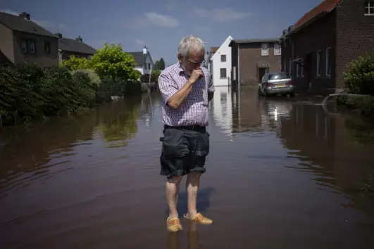  ?? Bram Janssen, The Associated Press ?? Wiel de Bie, 75, stands outside his flooded home Saturday in the town of Brommelen, Netherland­s. Troops piled sandbags to strengthen a stretch of dike along the Maas River, and police helped evacuate low-lying neighborho­ods.