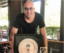  ?? ?? Top notch: Gill posing with the awards won by Tiki Taka, the restaurant formerly owned by him.