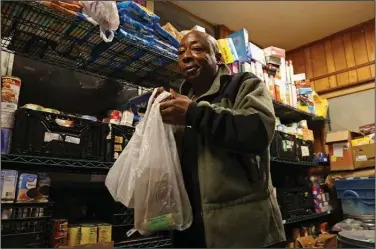  ?? (Arkansas Democrat-Gazette/Colin Murphey) ?? Douglas Miller grabs food from a pantry before preparing a traditiona­l Easter meal Sunday for those in need at the Little Rock Compassion Center.