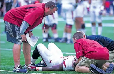  ?? NWA Democrat-Gazette/J.T. WAMPLER ?? Arkansas Coach Bret Bielema (left) watches trainers attend to running back Rawleigh Williams, who was injured during practice Saturday. Williams was taken by ambulance to an area hospital as a precaution after suffering a “stinger.”