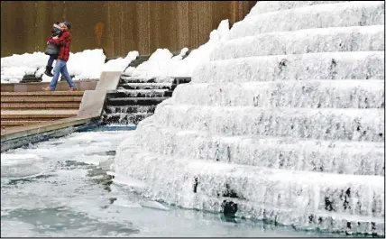  ?? Ap photo ?? Kenneth Freeman, carries his daughter Alora, 8, as they visit a frozen water fountain in downtown Atlanta yesterday.