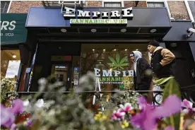  ?? JULIA NIKHINSON / AP ?? People walk past the Empire Cannabis Club on Wednesday in New York. Under pressure to launch one of the nation’s most hotly anticipate­d legal marijuana markets, the state Cannabis Control Board is set today to award dispensary licenses — a major step that comes as regulators stress they’re trying to stop unlicensed sellers.