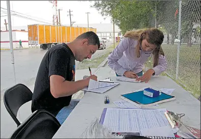  ?? AP/CHRISTOPHE­R SHERMAN ?? Aimee Gomez, a recruiter for assembly plants in Reynosa, Mexico, helps Juan Luis Alvarado de la Rosa fill out a job applicatio­n last month in an industrial park across the border from McAllen, Texas.