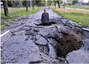  ?? ?? A man stands in a crater, created by a shell after a Russian attack in Kharkiv, Ukraine, to show its depth