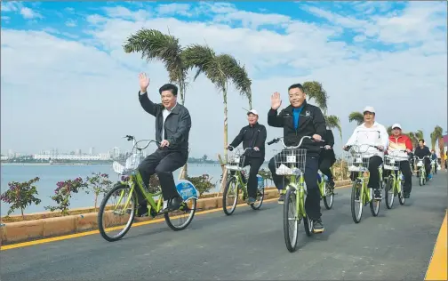  ?? LANG SHUCHEN / FOR CHINA DAILY ?? Wei Hongguang (left), Party chief of Zhanjiang, Mayor Wang Zhongbing and other local city officials ride bicycles around Binhu Park, the city’s largest lake wetland park, after the completion of reconstruc­tion on Dec 30, 2016.