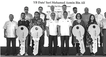  ??  ?? Azmin (in front, fourth right) during the photo session with the new apartment occupants yesterday. - Bernama photo