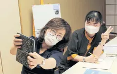  ??  ?? Jiho Yoshimizu takes a selfie with Thi Tu Luong, a Vietnamese migrant worker who came to the temple after losing her job at a hotel.