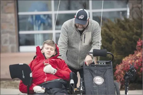  ?? (NWA Democrat-Gazette/J.T. Wampler) ?? Mike Fohner secures his son Josh into a bicycle seat in January at Lewis and Clark Outfitters in Springdale. Not content to watch a bike ride in his honor, Josh Fohner is training to go along.