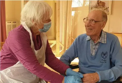  ??  ?? > Thelma Barnett, 82, holds her husband Basil, 83, by the hand for the first time in 12 months