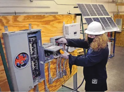  ??  ?? CNM student Phoenix Thompson uses a meter to check a power box in a CNM photovolta­ics class Feb. 10. Solar industry experts say there’s been an increase in demand lately for home installati­on of solar panels.