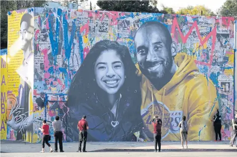  ??  ?? People take pictures of a mural of Kobe Bryant and his daughter Gianna in Los Angeles.