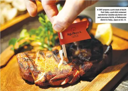  ??  ?? A CHEF prepares a pork steak at HyLife Pork Table, a pork dish restaurant operated by Canadian pig farmer and pork processor HyLife, at Daikanyama district in Tokyo, Japan on Oct. 31.