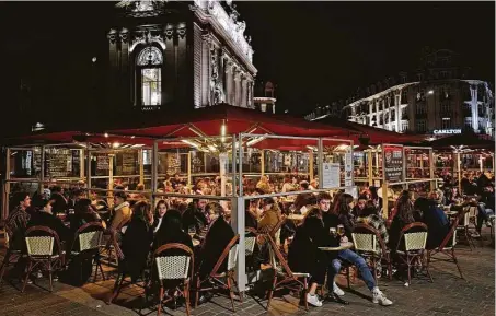  ?? Michel Spingler / Associated Press ?? A crowd enjoys a meal in Lille, northern France. The nation is deploying 12,000 police officers to enforce a new curfew coming into effect Friday night for the next month to slow the virus spread, and it will spend another 1 billion euros to help businesses.