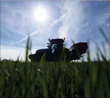  ?? BLOOMBERG PHOTO BY CHRIS RATCLIFFE. ?? A tractor spreads fertilizer onto a field of wheat.