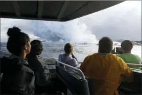  ?? JAE C. HONG — THE ASSOCIATED PRESS FILE ?? People watch a plume of steam as lava enters the ocean near Pahoa, Hawaii. Officials say an explosion sent lava flying through the roof of a tour boat off the Big Island, Monday injuring at least 13 people. The people were aboard a tour boat that takes visitors to see lava from an erupting volcano plunge into the ocean.