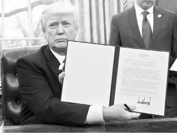  ?? — AFP photo ?? US President Donald Trump holds up an executive order withdrawin­g the US from the Trans-Pacific Partnershi­p after signing it in the Oval Office of the White House in Washington, DC, January 23. Trump the decree Monday that effectivel­y ends US...