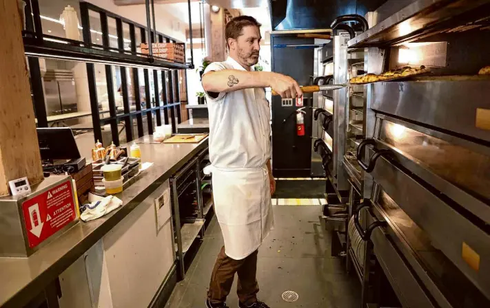  ?? Scott Strazzante/The Chronicle ?? Chef Elliott Armstrong removes a pizza from a PizzaMaste­r electric oven at Flour + Water Pizzeria. The ovens have proven highly capable, owners say.