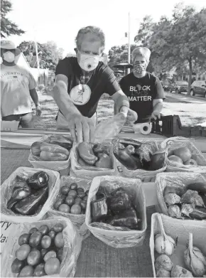  ?? RICK WOOD/MILWAUKEE JOURNAL SENTINEL ?? Edgar Russell (from left) and Pastor Daniel and Sarah Czaplewski of Mount Calvary Lutheran Church set out produce at the Vliet Street stand. The produce was grown by Mount Calvary Urban Farms.