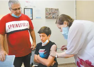  ?? UPI-Yonhap ?? A nurse injects an Israeli youth with the Pfizer BioNTech COVID-19 vaccine at a Maccabi Health Center in Jerusalem, Tuesday. Israeli health services have seen a rise in youth (12-15 years) being vaccinated after the appearance of the Delta variant in Israel.