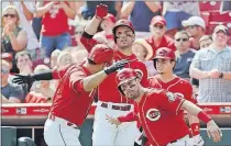  ?? THE ASSOCIATED PRESS] [JOHN MINCHILLO/ ?? The Reds’ Eugenio Suarez, left, celebrates with Jesse Winker, right, after hitting a two-run home run in the sixth inning. The Reds’ Joey Votto looks on.