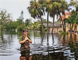  ??  ?? Flooded: A local wades through Bonita Springs to her home