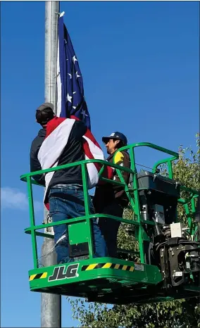  ?? RECORDER PHOTO BY ESTHER AVILA ?? Thomas James, left, and Alvino Levario attach a 10-15-ft. American flag to clips in preparatio­n of hoisting the flag to the top of the flag pole Tuesday morning. The flag will fly through Flag Day, when a new 22x40 foot flag will be raised.