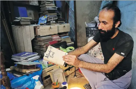  ?? REEM SAAD/ THE ASSOCIATED PRESS ?? Hamzeh AlMaaytah sorts books at his Mahall al-Maa bookstore, in Jordan’s capital, Amman.