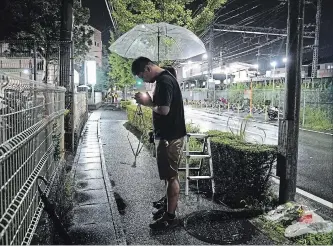  ?? JAE C. HONG THE ASSOCIATED PRESS ?? A couple prays after placing flowers near the Kyoto Animation building, which does work on movies and TV production­s, after the studio suffered a shocking attack and brought an outpouring of grief from anime fans.