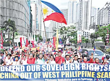  ??  ?? Anti-China protesters, carrying national flags and placards, march towards the Chinese consular office in a protest in the financial district of Manila. — AFP photo