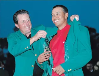  ?? MORRY GASH THE ASSOCIATED PRESS ?? Tiger Woods, right, gets the Green Jacket from Phil Mickelson after winning the 2005 Masters at the Augusta National Golf Club in Augusta, Ga. Woods is back for only the second time in the last five years.