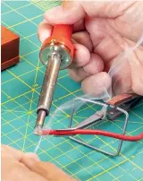  ??  ?? Tinning a stripped wire while it’s held in a clamp makes it an easy job. Apply heat to the wire end, then the solder. When the solder starts to flow, remove the iron and feed solder in as it wicks.