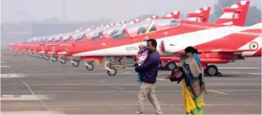  ?? Associated Press ?? ↑
A family walks past Indian Surya Kiran aircraft ahead of an aerobatic aerial display at the Air Force station in Kalaikunda, West Bengal, on Friday.