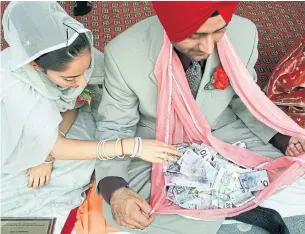  ?? ANDREW STAWICKI TORONTO STAR FILE PHOTO ?? In Sikh weddings, like these 2002 Mississaug­a nuptials, money has an open place in the ritual, with bills here being deposited by guests into the bride’s scarf (known as a pala).