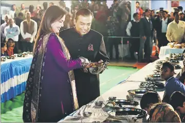  ?? — AFP photos ?? This handout photograph taken on Dec 7 and released by the Ambani family via Reliance Industries shows Reliance Industries chairman Mukesh Ambani (second left) and his wife Nita (left) serving food to guests during an ‘Anna Seva’ ritual that coincides with pre-wedding functions ahead of the marriage of their daughter Isha with Anand Piramal, the son of Indian industrial­ist Ajay Piramal, in Udaipur.