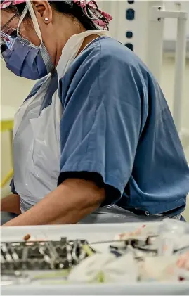  ?? CHRIS SKELTON/ STUFF ?? Dr Arun Natarajan, left, a paediatric dental specialist at Christchur­ch Hospital, removes 10 rotten teeth from a 3-year- old child. He says research shows poverty is linked to poor oral health.