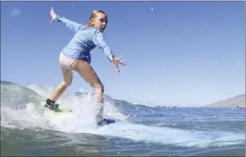  ?? The Maui News / MATTHEW THAYER photos
Reagan Riley of Seattle catches a wave Friday while taking a surf lesson at Kalama Park near Cove Park in Kihei. ??